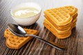 Bowl with condensed milk, stack of cookies, spoon on biscuit on wooden table