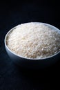 White bowl containing uncooked white rice against a black background. Royalty Free Stock Photo