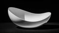 A white bowl with a curved shape sits on a black surface. Royalty Free Stock Photo