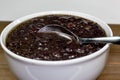 White bowl filled with black bean soup and a spoon ready to eat on the kitchen table Royalty Free Stock Photo