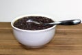 White bowl filled with black bean soup and a spoon ready to eat on the kitchen table Royalty Free Stock Photo