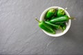 A white bowl filled with bright green jalapeno peppers rests on a gray slate cutting board Royalty Free Stock Photo