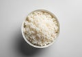A white bowl filled with cooked rice is placed against a plain, light-colored Royalty Free Stock Photo