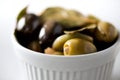 White bowl with fresh black and green olives, garlic, bay leaves on grey background. Copy space Royalty Free Stock Photo