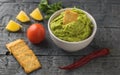 White bowl with fresh guacamole, lemon, tomatoes and garlic on wooden table. Diet vegetarian Mexican food avocado. Royalty Free Stock Photo