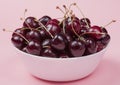 White bowl of fresh red cherries on a pink background. close-up Royalty Free Stock Photo