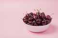 White bowl of fresh red cherries on a pink background. Copy space. close-up Royalty Free Stock Photo