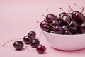 White bowl of fresh red cherries on a pink background. Copy space. close-up Royalty Free Stock Photo