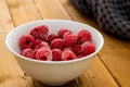 White bowl of frozen raspberries on a wooden table Royalty Free Stock Photo