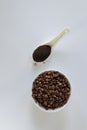 White bowl full of coffee beans and spoonful of ground coffee on background Royalty Free Stock Photo