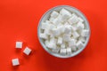 White bowl full with sugar cubes isolated on a red background Royalty Free Stock Photo