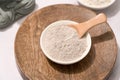 White bowl with gray cosmetic clay on wooden tray - mineral powder