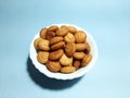 A white bowl with home made biscuits in cashew shaped with sky colour background. Usful for bakery, confectioneries.