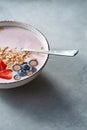 White bowl with homemade granola, sliced strawberries, yogurt, blueberry, spoon - natural breakfast on a gray table. Royalty Free Stock Photo