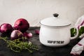 White bowl and lid with soup of the day lettering, red onions and herbs on black and white background Royalty Free Stock Photo