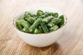 White bowl with marmalade in form green bean on wooden table Royalty Free Stock Photo