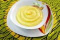 A white bowl of Nigerian cereal Ogi or pap on a green tablecloth