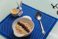 White bowl of oatmeal porridge with blueberries, almond flakes, nuts. Pot of honey and spoon on blue napkin on kitchen table Royalty Free Stock Photo