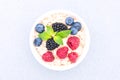 White bowl with oatmeal porridge served with raspberries, blueberries and blackberries on concrete table background Royalty Free Stock Photo