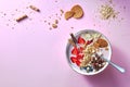 A white bowl of organic yogurt smoothie with strawberries, banana, blueberry, oat flakes and biscuits on pink background Royalty Free Stock Photo