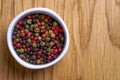 White bowl with pepper mix, top view. Various pepper served in white bowl on wooden background. Royalty Free Stock Photo