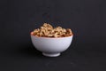 White bowl with a pile of shelled walnuts on a black surface Royalty Free Stock Photo