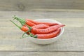 White bowl with red hot chili peppers on wooden background Royalty Free Stock Photo