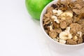 White bowl with rye flakes muesli on white towel with green apple, copyspace, white background