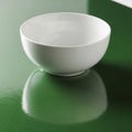 White bowl on a shiny, textured green surface. The bowl is smooth and reflective, Royalty Free Stock Photo