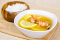 White bowl with traditional light spicy thai cuisine tom yam soup with shrimps, seafood and lemon on wooden board background. Royalty Free Stock Photo