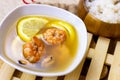 White bowl with traditional light spicy thai cuisine tom yam soup with shrimps, seafood and lemon on wooden board background.