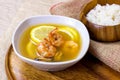 White bowl with traditional light spicy thai cuisine tom yam soup with shrimps, seafood and lemon on wooden board background. Royalty Free Stock Photo