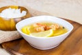 White bowl with traditional light spicy thai cuisine tom yam soup with shrimps, seafood and lemon on wooden board background. Royalty Free Stock Photo