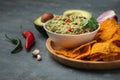White bowl of traditional Mexican guacamole with nachos on grey concrete background. Tortilla chips with guacamole sauce dip and Royalty Free Stock Photo
