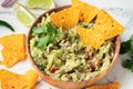 White bowl of traditional Mexican guacamole with nachos on white marble background. Tortilla chips with guacamole sauce dip and Royalty Free Stock Photo