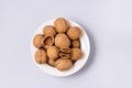 White Bowlof Walnut Kernels and Whole Walnuts on Blue Background Top View Horizontal