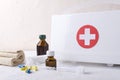 White box for first aid, pills, syringe, bandage, glasses of medicines on the white table against light background Royalty Free Stock Photo