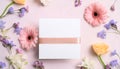 A white box with a pink ribbon sits on a table with flowers Royalty Free Stock Photo