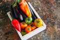 White box with vegetables on a rusty background. Aubergines, bell pepper, tonatoes. Royalty Free Stock Photo