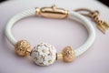 white bracelet with delicate gold details and charm