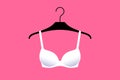 White brassiere is on hanger over bright pink background