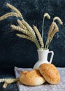 White bread rolls decorated with wheat ears in white vase on dark background Royalty Free Stock Photo