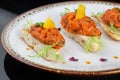 white bread sandwich with red fish on a white plate. salmon appetizer garnished with herbs and orange