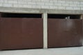 White brick garage facade with two brown iron gates