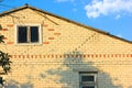 A white brick two-storey house with a crack under a roof. A damaged building Royalty Free Stock Photo