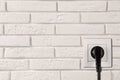 Brick wall with power socket and inserted plug, space for text. Electrical supply Royalty Free Stock Photo