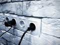 White brick wall with white socket for four cells and two black plug Royalty Free Stock Photo