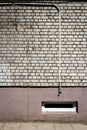 White brick wall with some cables and basement window Royalty Free Stock Photo
