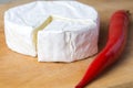 White brie cheese on the kitchen board with red chot chili paper