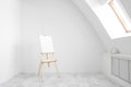 White and bright studio with a window. Workspace of the artist. Easel, canvases and plaster figures for learning to draw